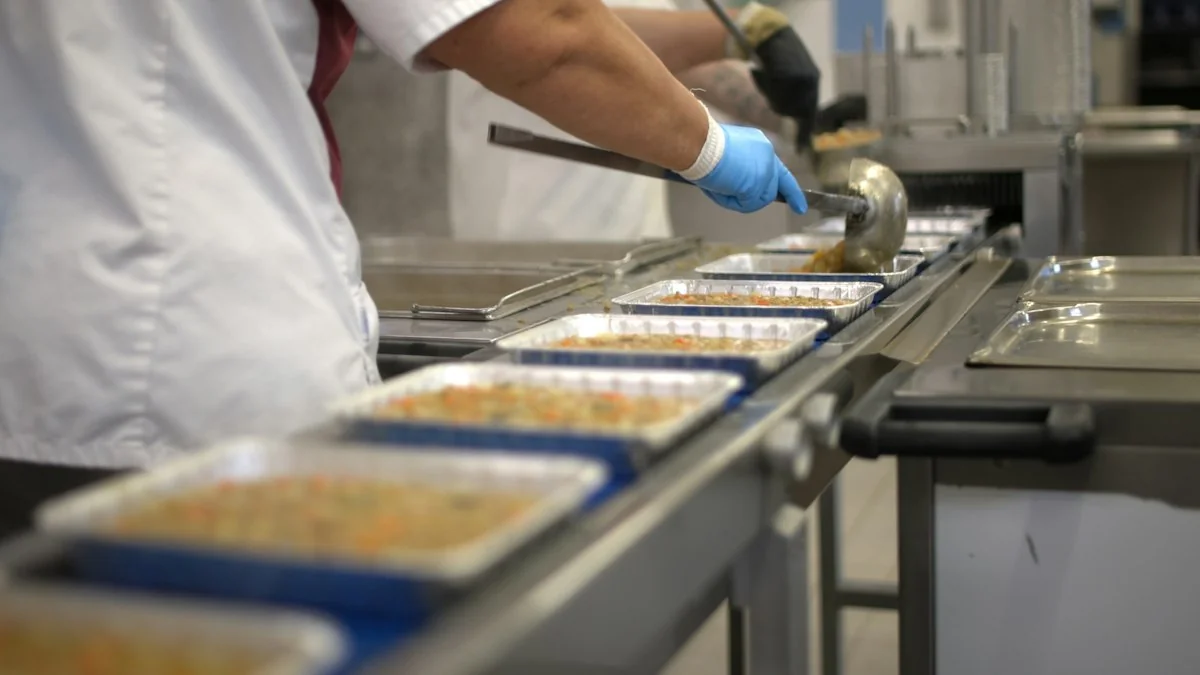 Trabajador envasando alimentos en línea de producción